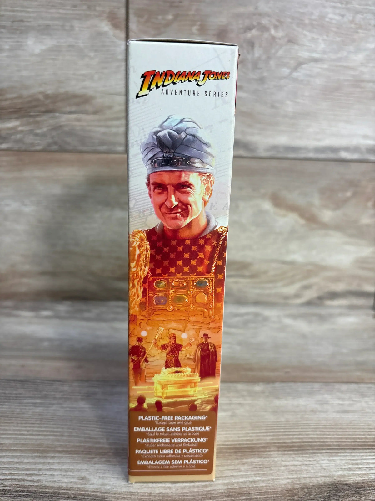 Side view of Rene Belloq action figure box showing Belloq and Ark artwork and plastic free packaging label on wood background