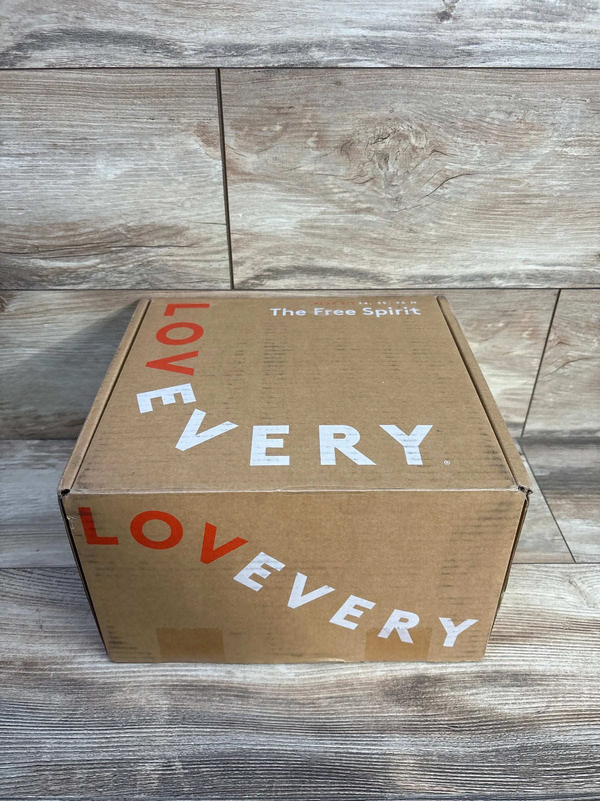 Front view of Lovevery The Free Spirit Play Kit box showcasing Lovevery branding and The Free Spirit title against a wood-patterned background