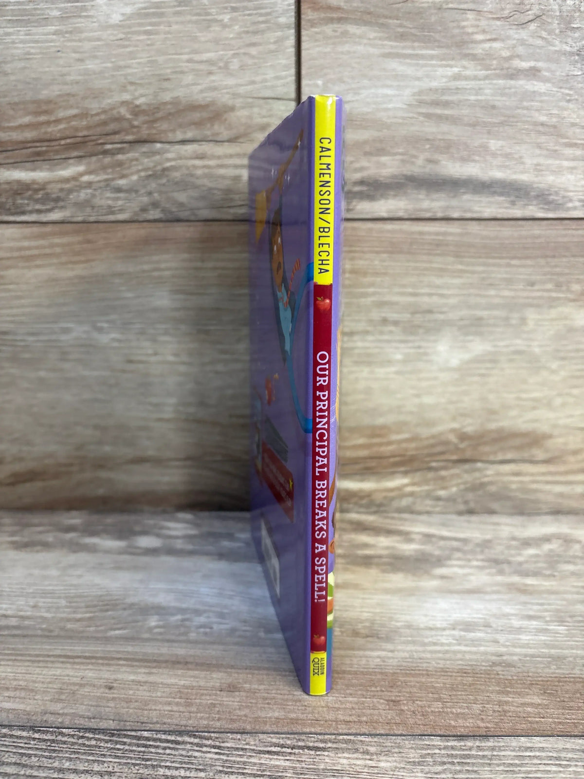Children's book spine titled 'Our Principal Breaks a Spell' against wood background