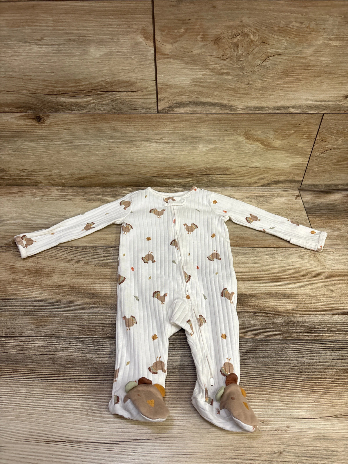 Front view of Just One You white ribbed turkey sleeper showcasing long sleeves, turkey print, and footed design on a wood floor