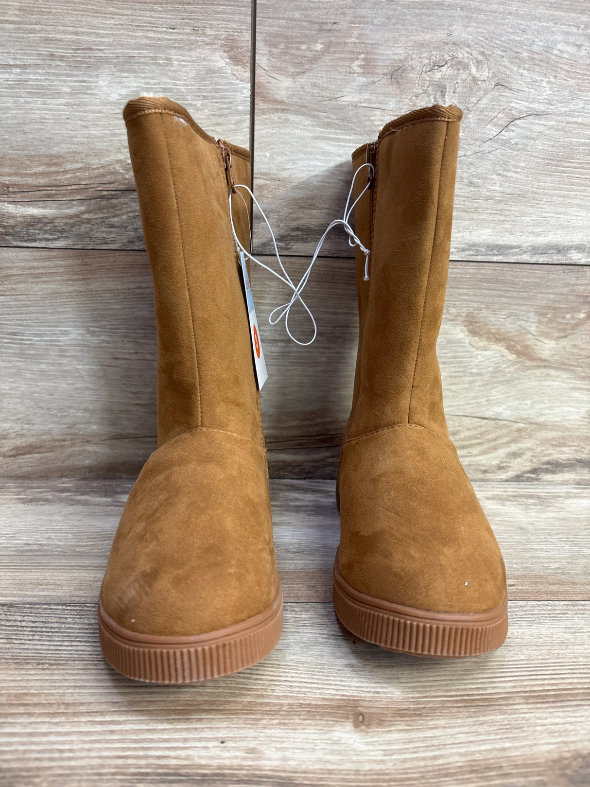 Pair of brown suede kids boots with side zippers on wood floor