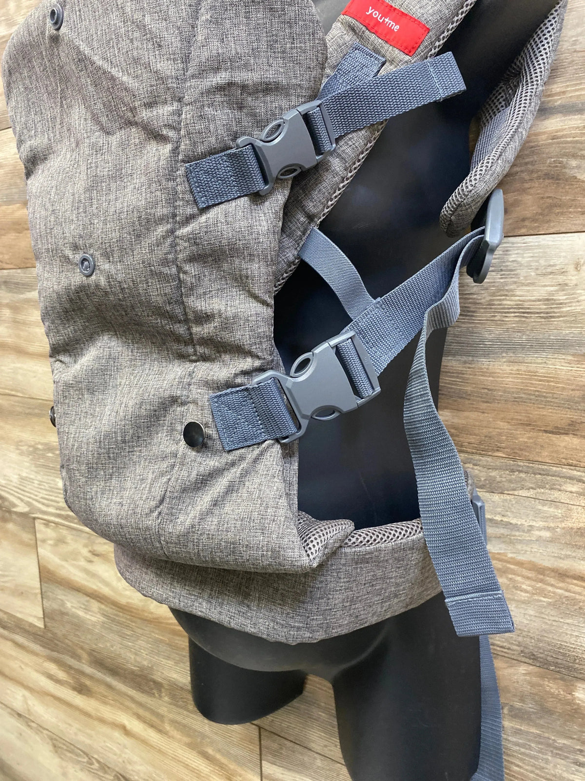 Side close up of grey You Me 4-in-1 baby carrier showing buckles and adjustable straps on a black mannequin