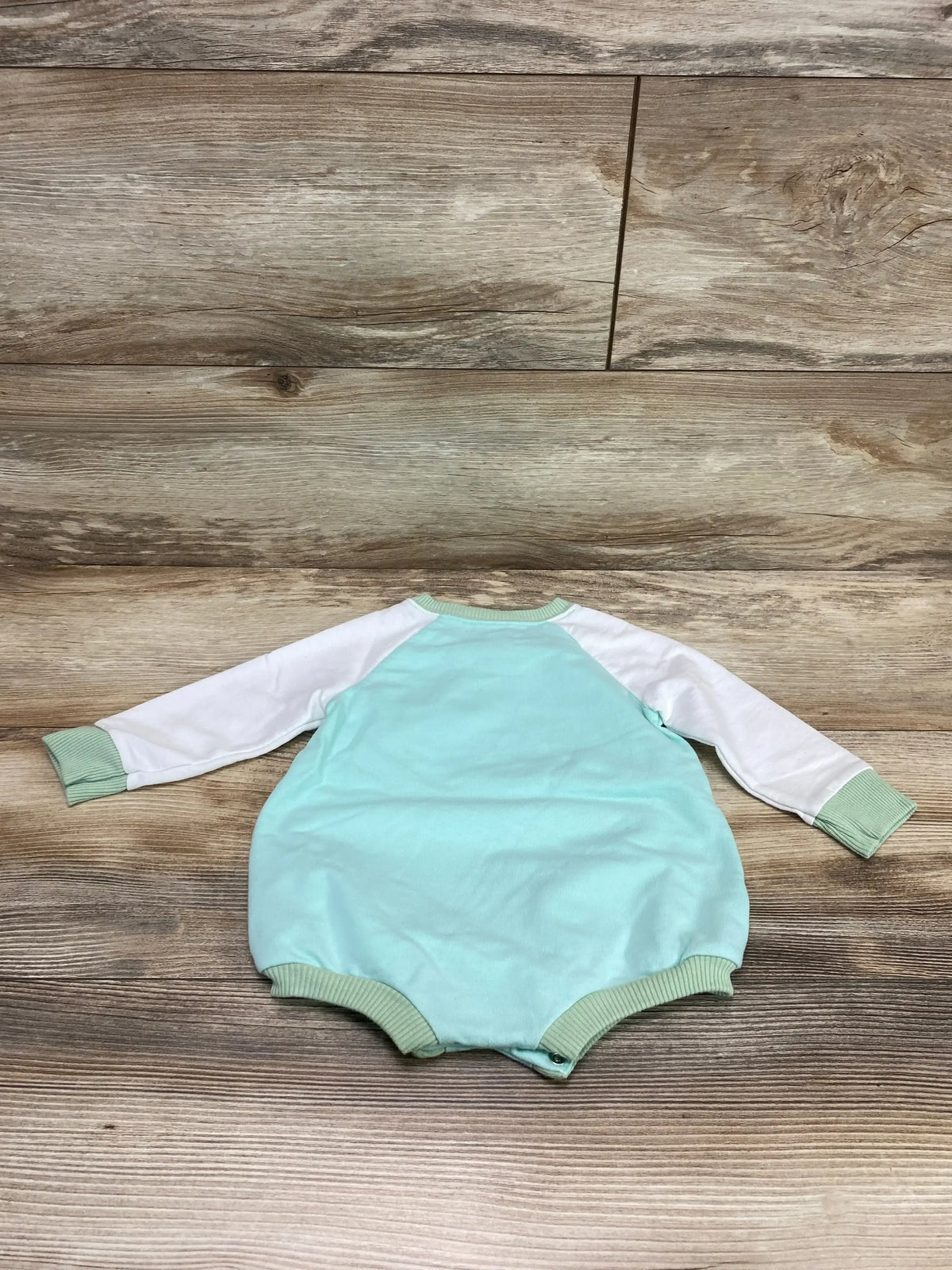 Back view of Cat & Jack Little Love romper in mint with white raglan sleeves, ribbed cuffs and snap crotch on wood floor