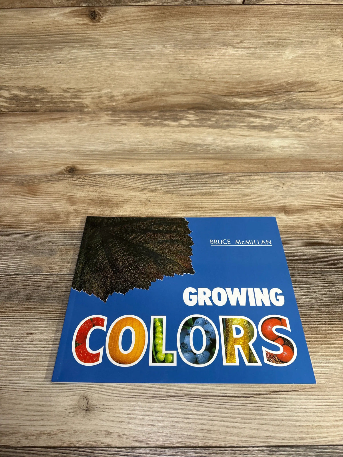 Children's book Growing Colors by Bruce McMillan with nature-themed colorful letters on wooden table