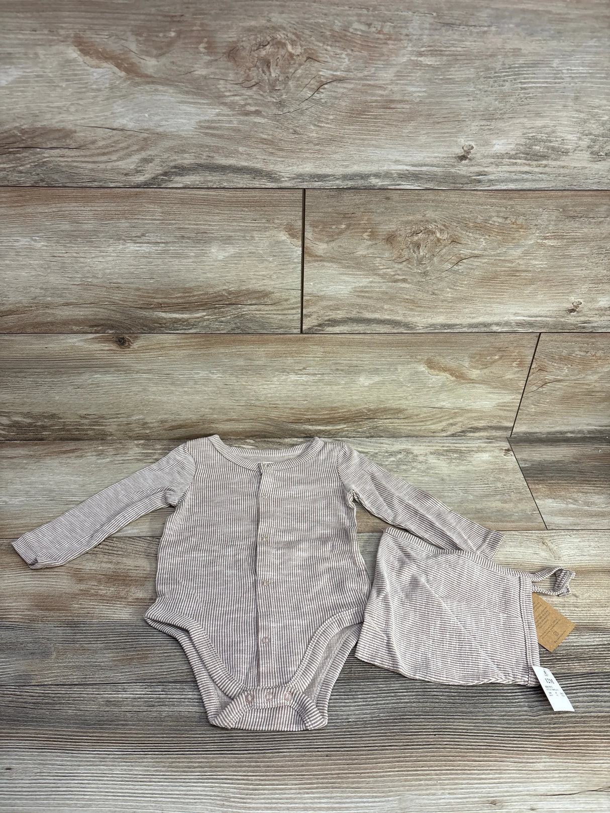 Striped long sleeve baby bodysuit and matching hat set on wood background