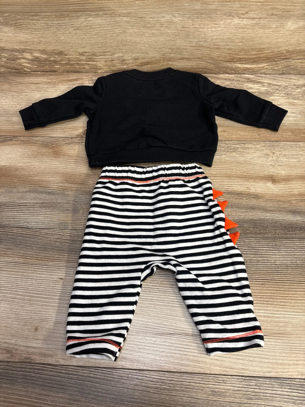 Top view of Cat & Jack Milk Monster set showcasing black sweatshirt, striped joggers, and orange spikes on wood grain