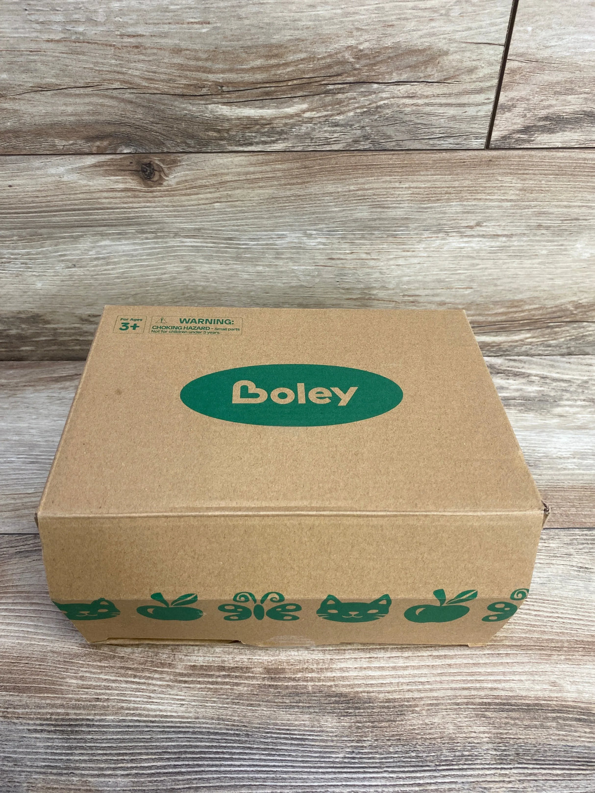 Boley cardboard toy box with green animal and fruit icons on a wood background