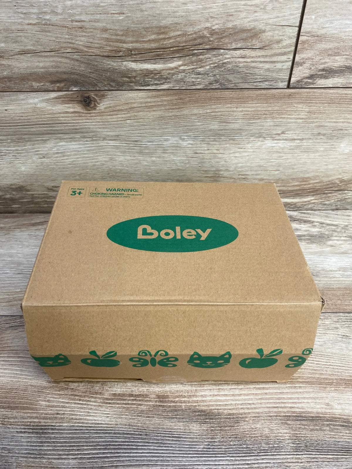 Boley cardboard toy box with green animal and fruit icons on a wood background