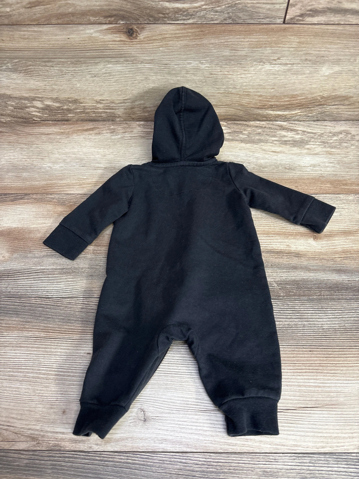 Black hooded one-piece baby romper on wooden floor for kids clothing resale