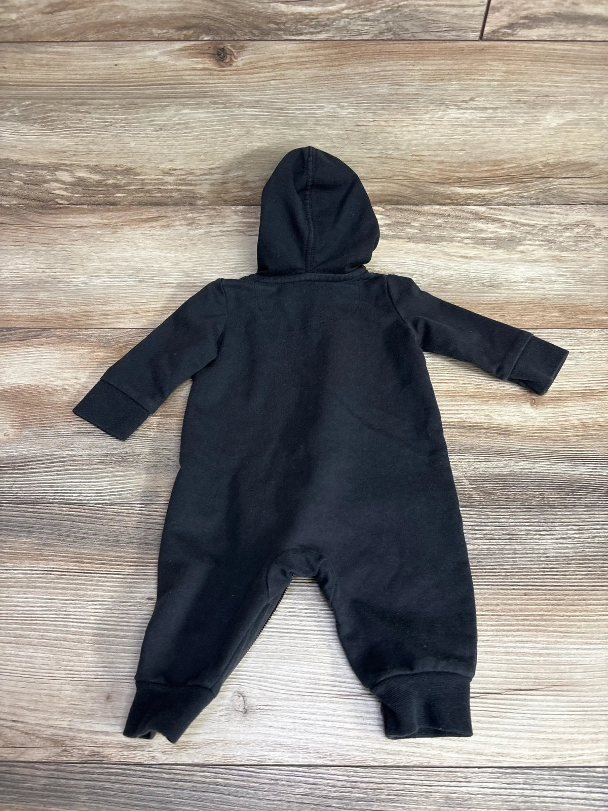 Black hooded one-piece baby romper on wooden floor for kids clothing resale
