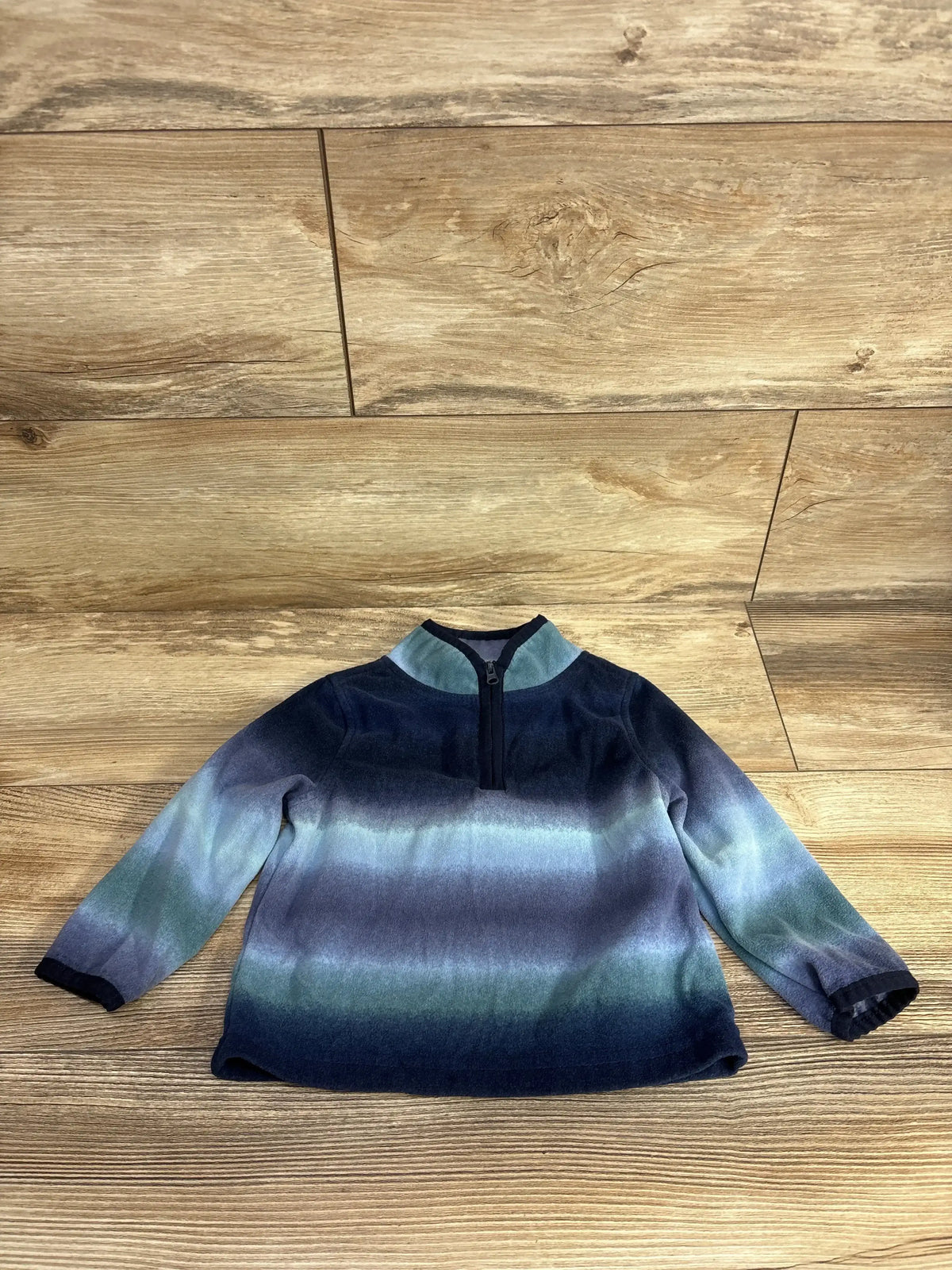 Long sleeve toddler pullover sweater with blue and green ombre stripes on wood floor