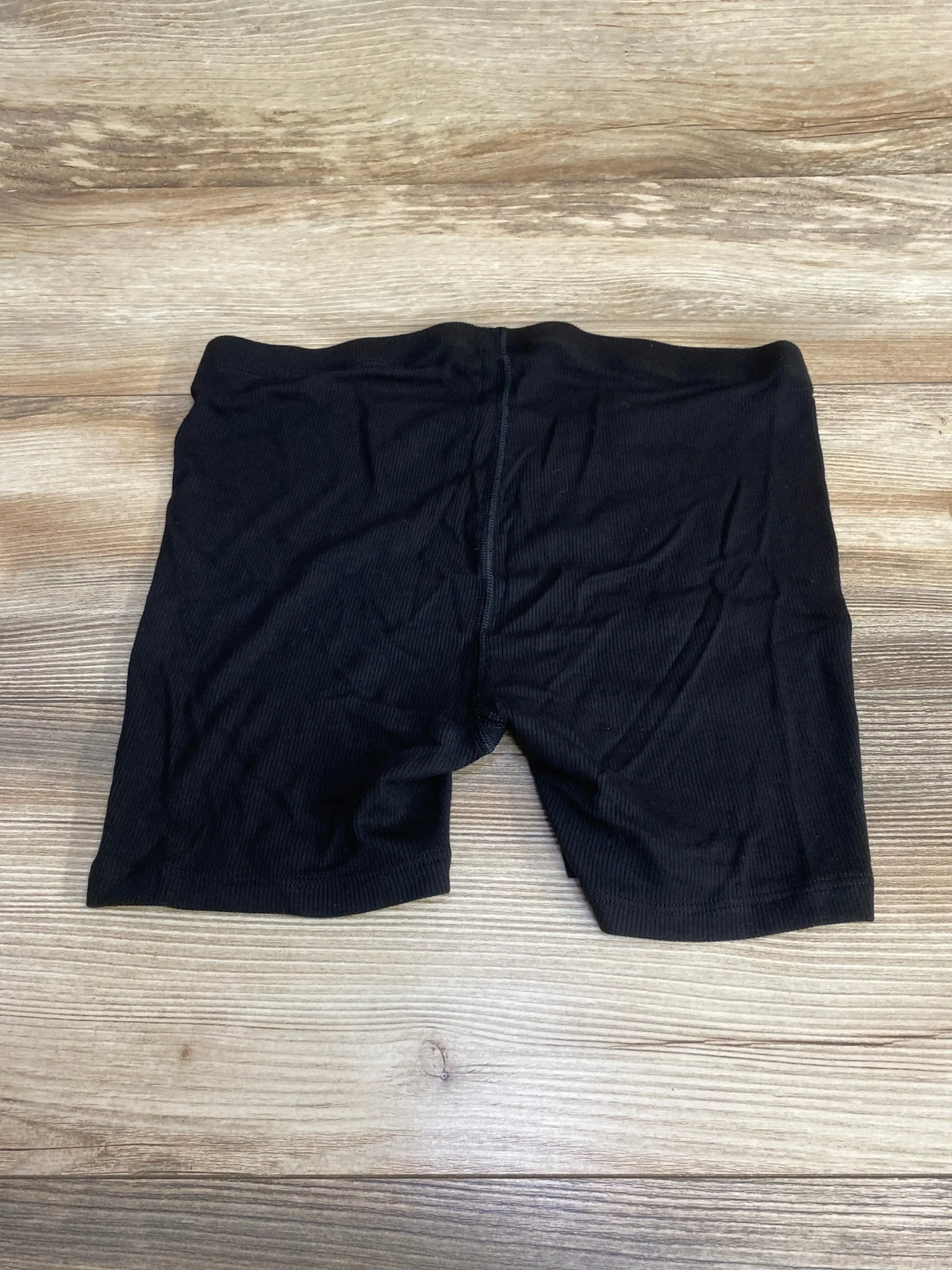 Flat-lay back view of black rib-knit maternity PJ shorts showing high elastic waistband panel and mid-thigh length on wood background