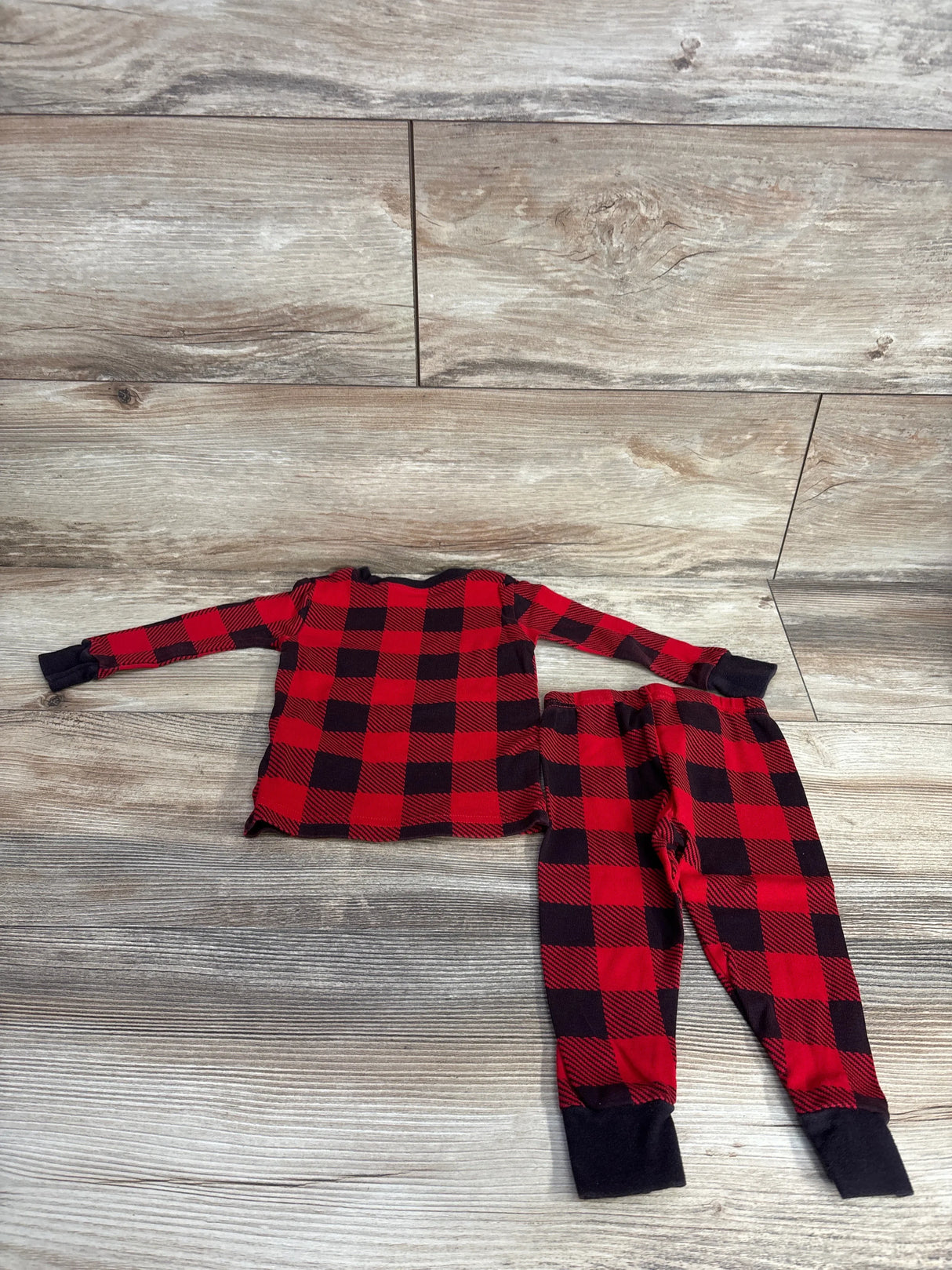 Red and black plaid kids pajama set on wooden floor