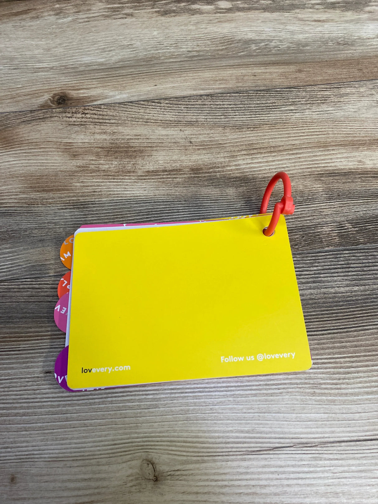 Colorful laminated flashcards with rounded tabs on a wooden surface, secured with a red ring, featuring lovevery.com branding