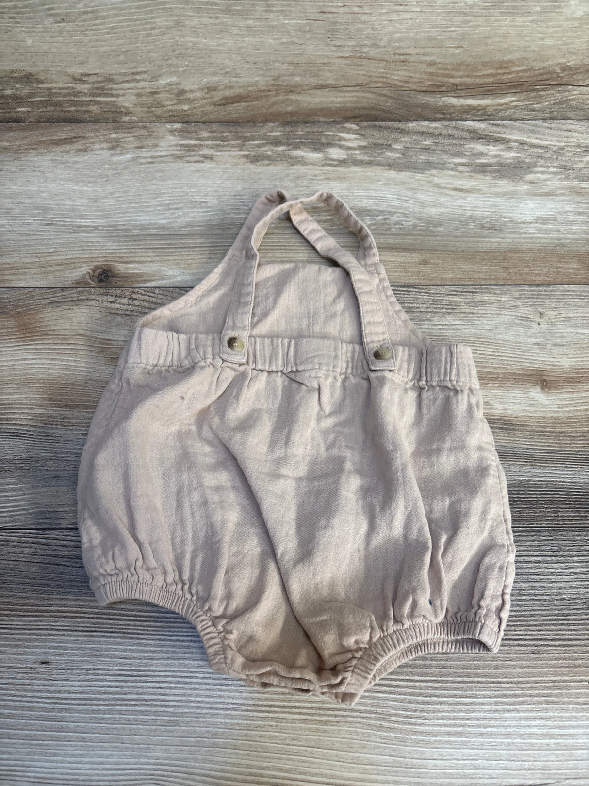 Front view of Siix Sleeveless Bubble Romper Beige sz 12-18m showcasing shoulder straps and elastic leg openings on a wood floor
