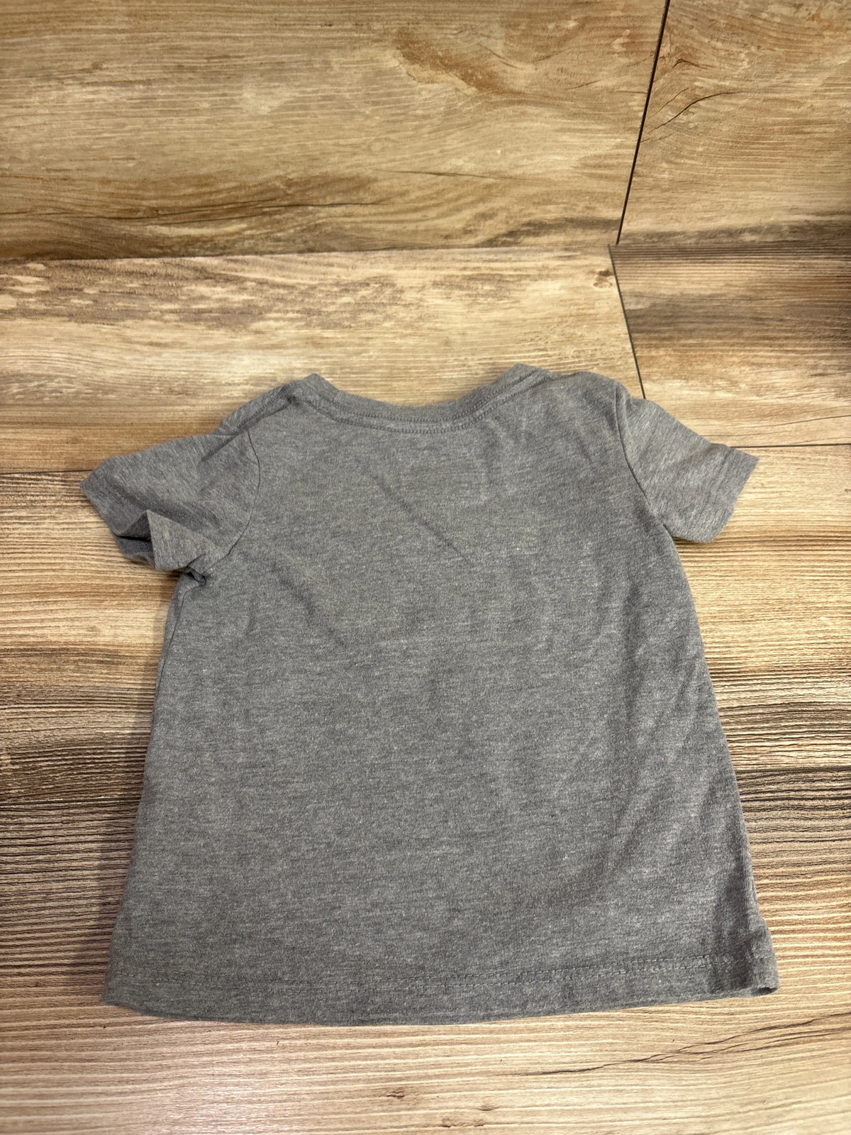 Back view of gray Cat and Jack Brother Club shirt with short sleeves on a wood surface