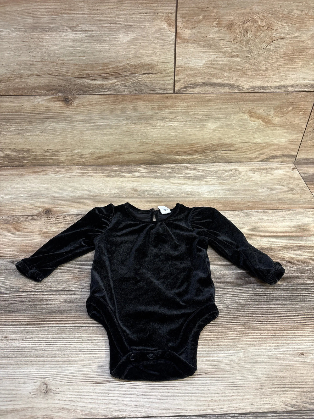 Old Navy black velvet long sleeve baby bodysuit for 3-6 months on a wood background