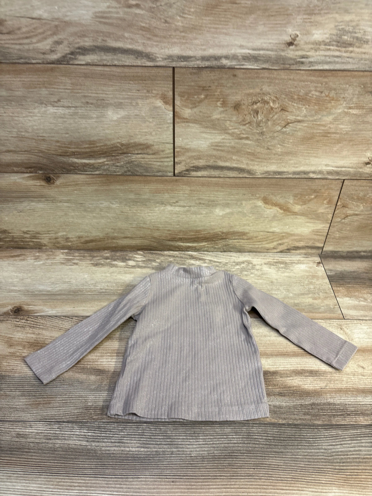 Front view of Oshkosh tan ribbed metallic long-sleeve shirt, size 12m, on a wood background