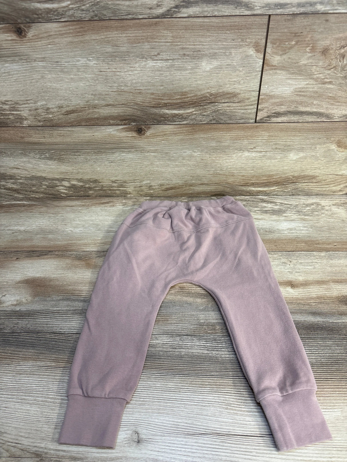 Front view of Little Bipsy Joggers Oat sz 3-4T showcasing ribbed waistband and ankle cuffs on wood background