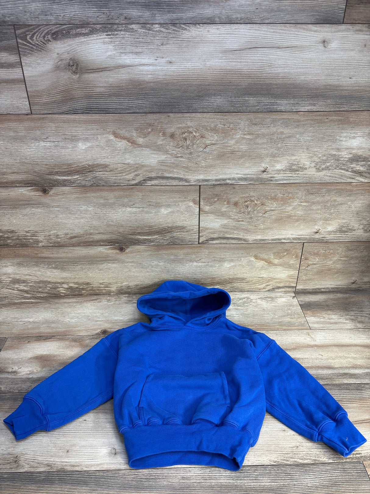 Bright blue kids hoodie on wood floor, cozy cotton sweatshirt, long sleeves, kangaroo pocket