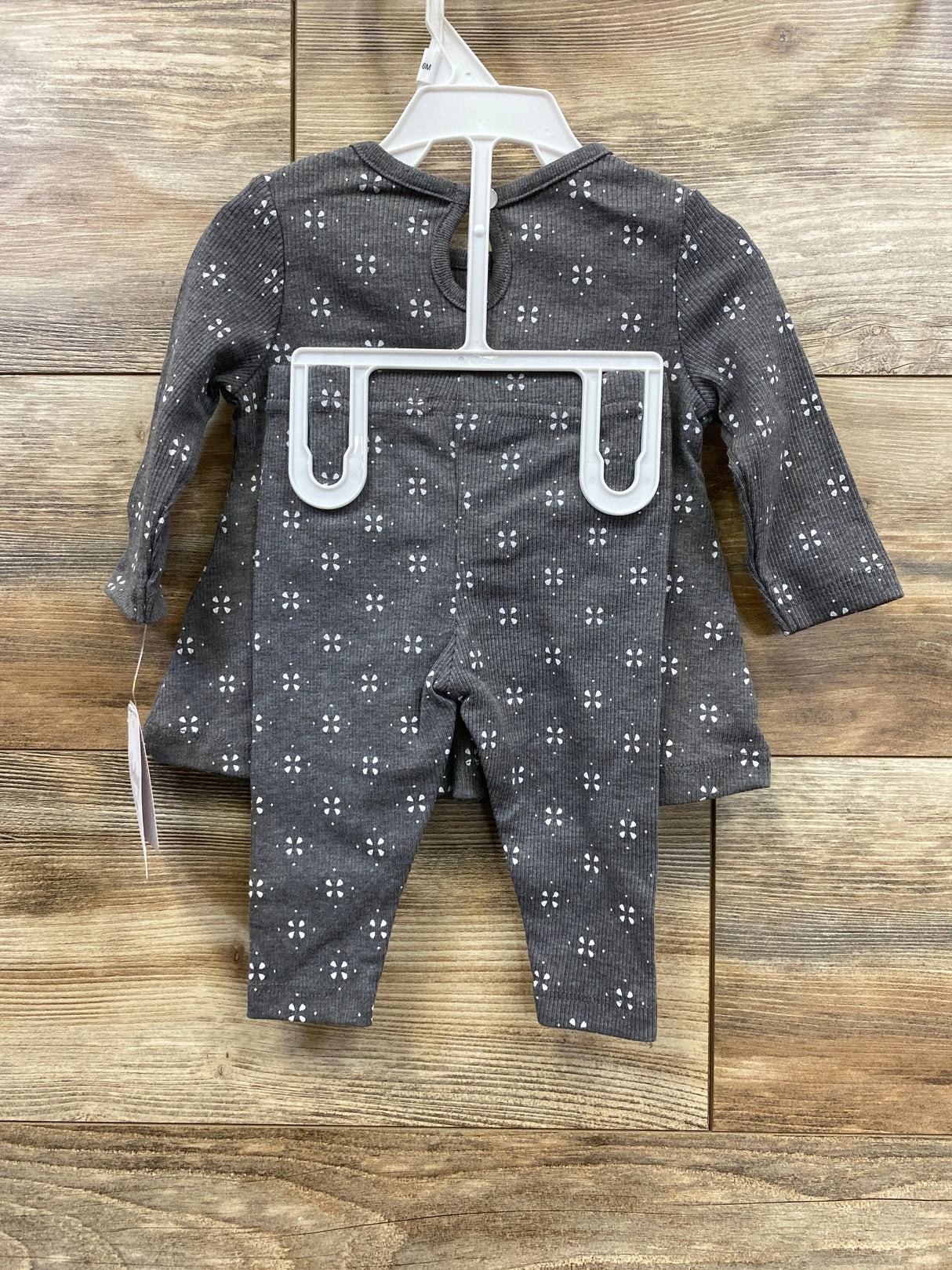 Gray baby outfit with white floral pattern, long sleeves and pants, on hanger
