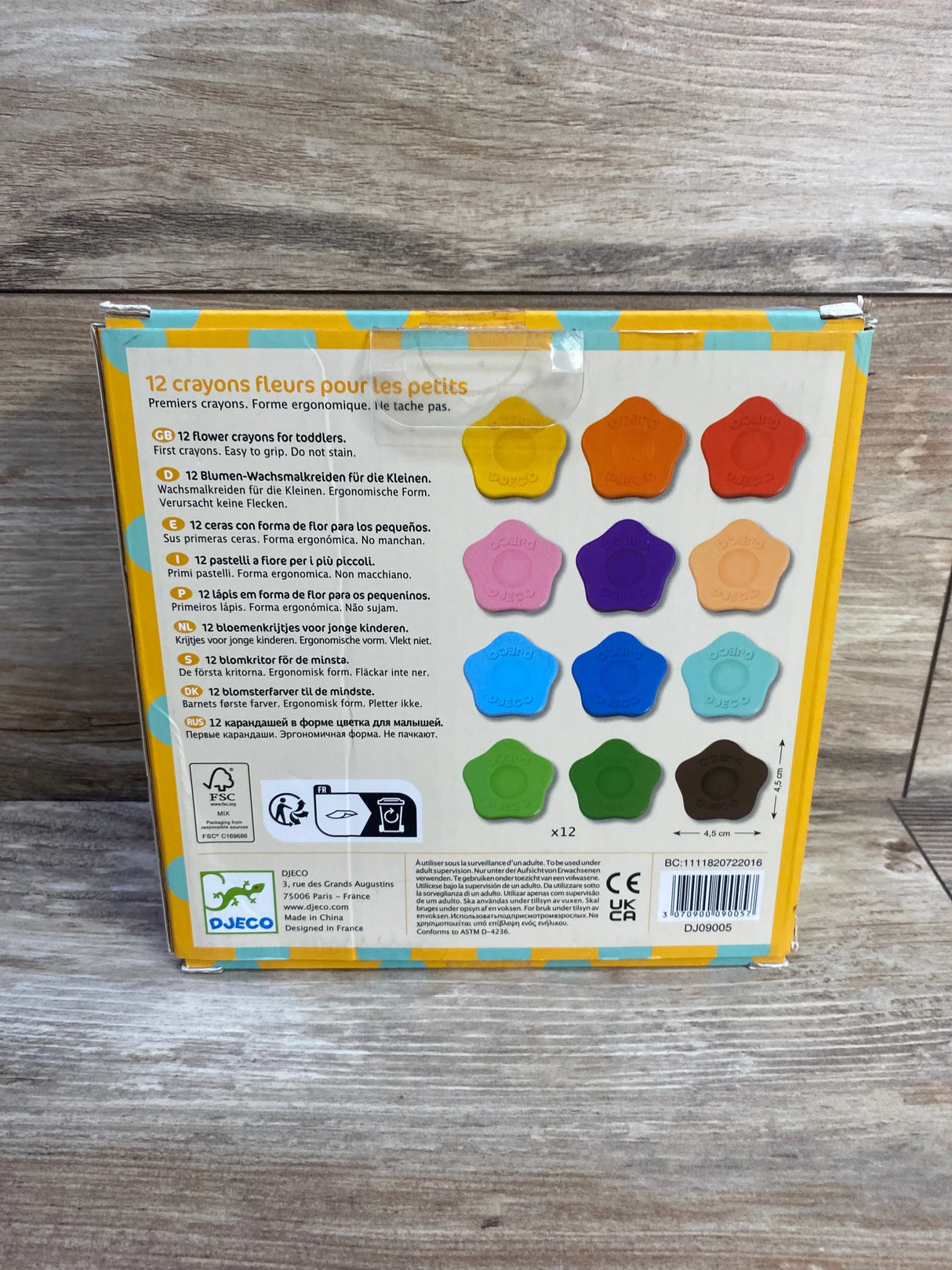 Back of Djeco box showing 12 flower-shaped lightweight crayons in assorted colors with packaging text and wood background