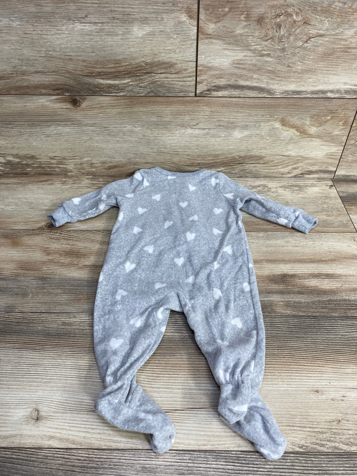 Gray baby onesie with white heart patterns on wooden floor