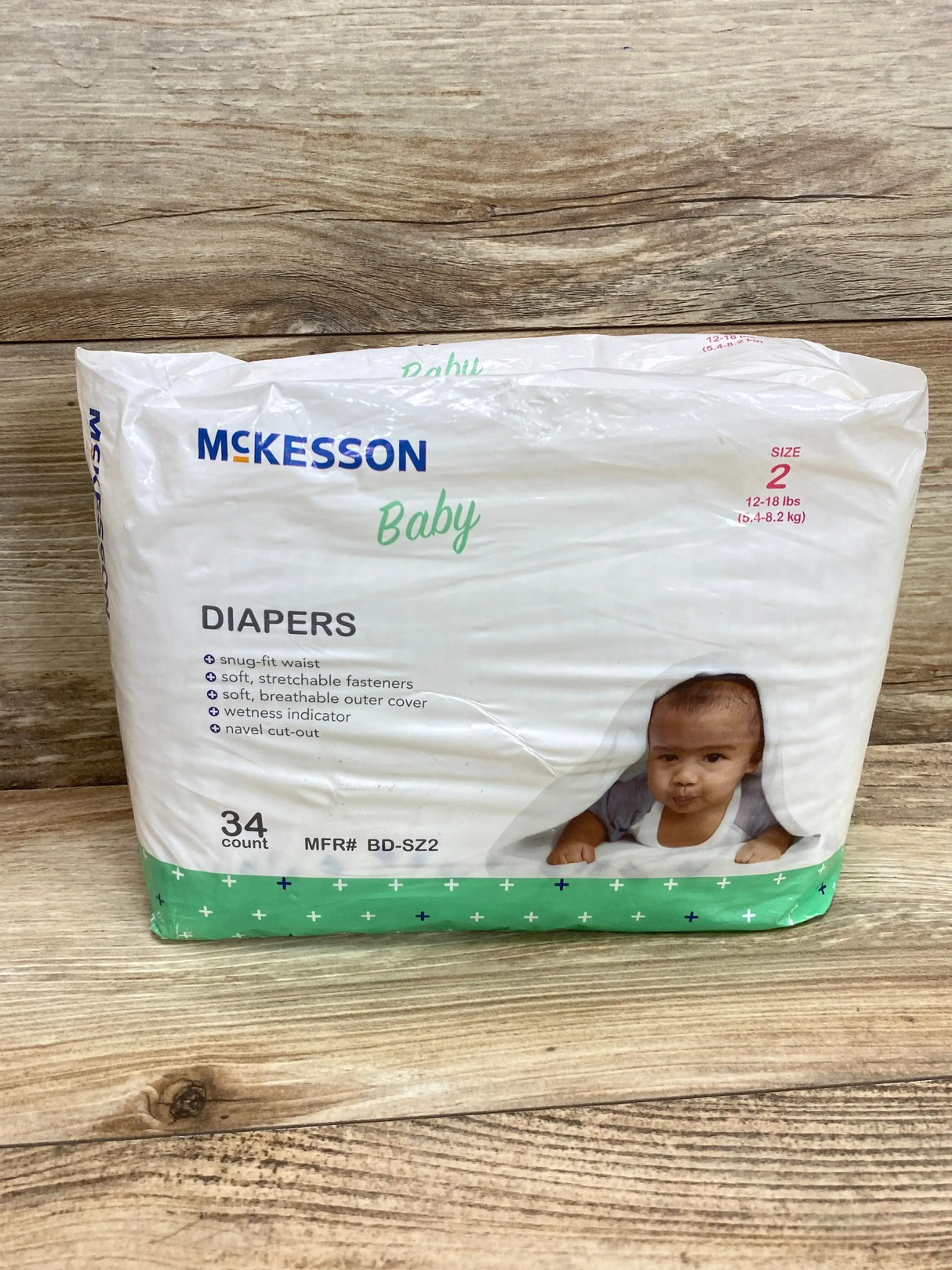 Front view of McKesson Baby Diapers pack, Size 2 34 count, showing brand, features list and baby photo on wood background