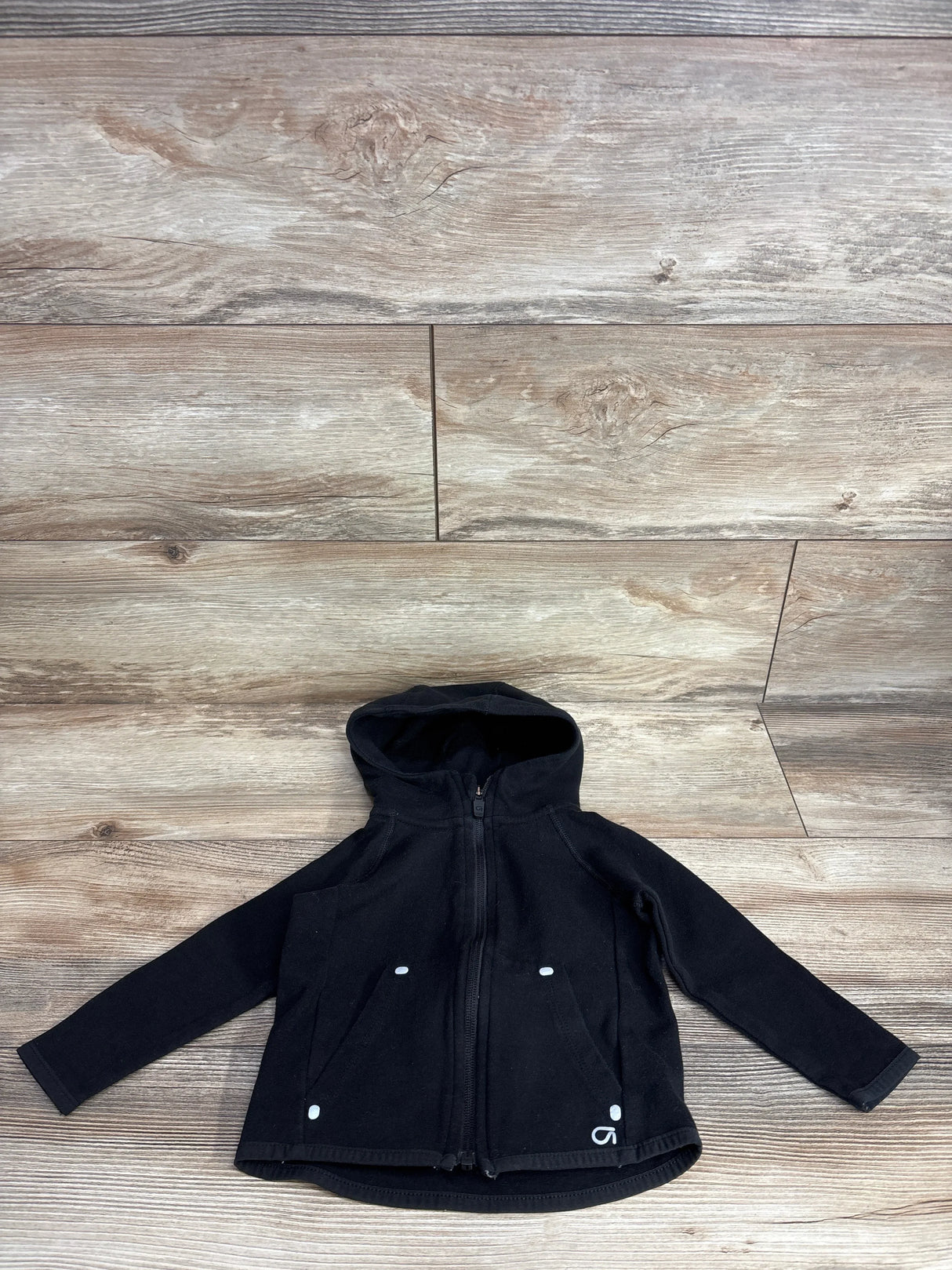 Black hooded kids jacket with zip front and pockets on wood background