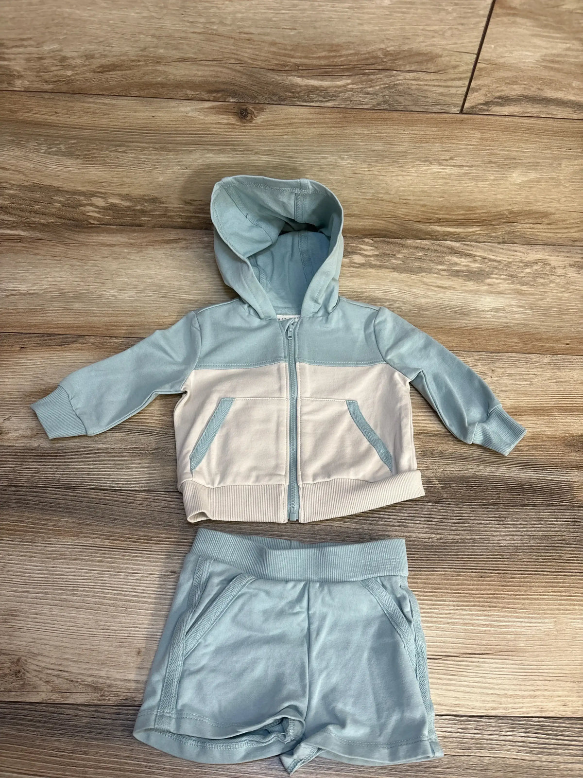 Baby two-piece set with light blue hoodie and matching shorts on wooden floor