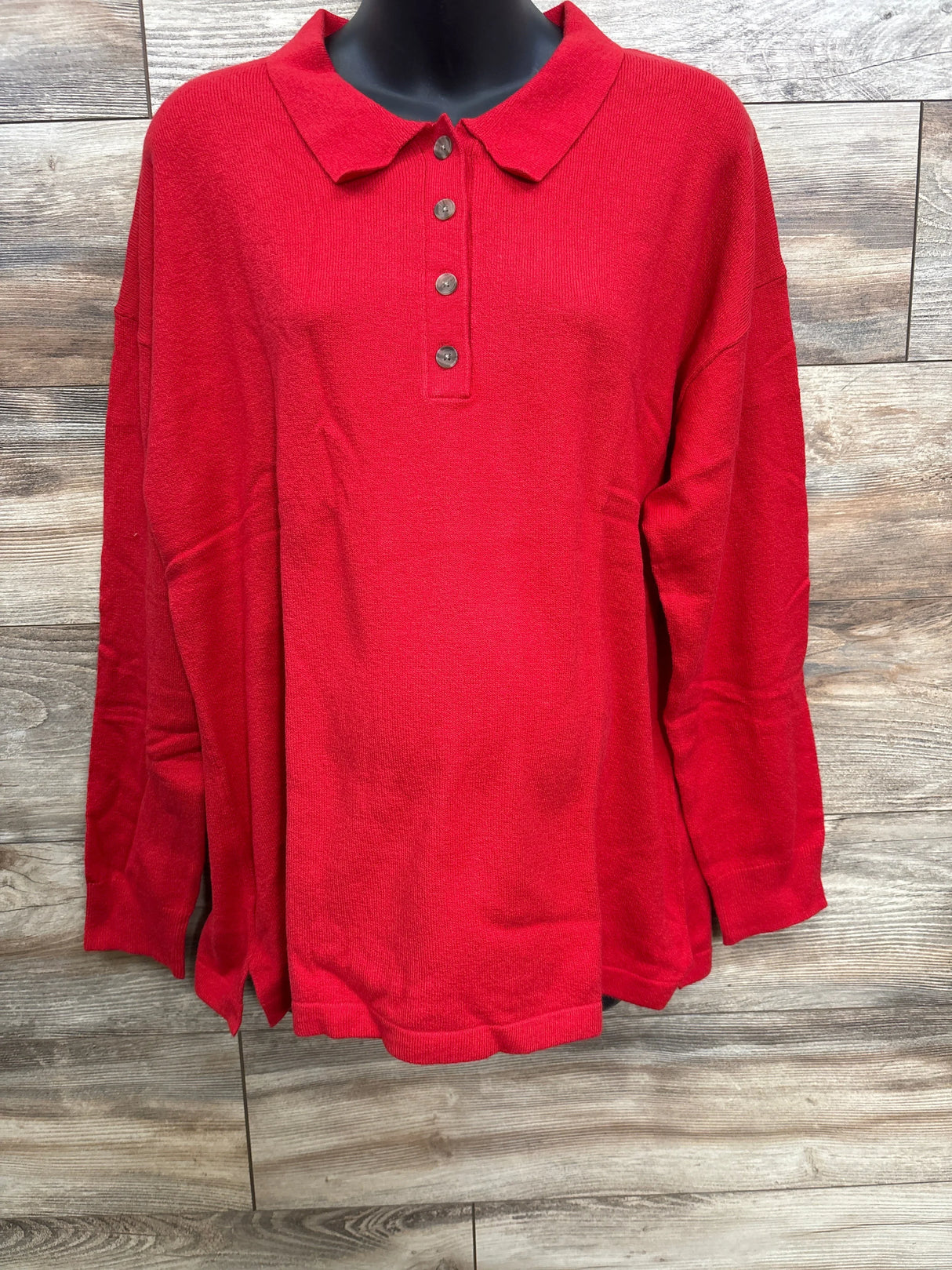Red long-sleeve knit polo shirt with buttons on wooden background
