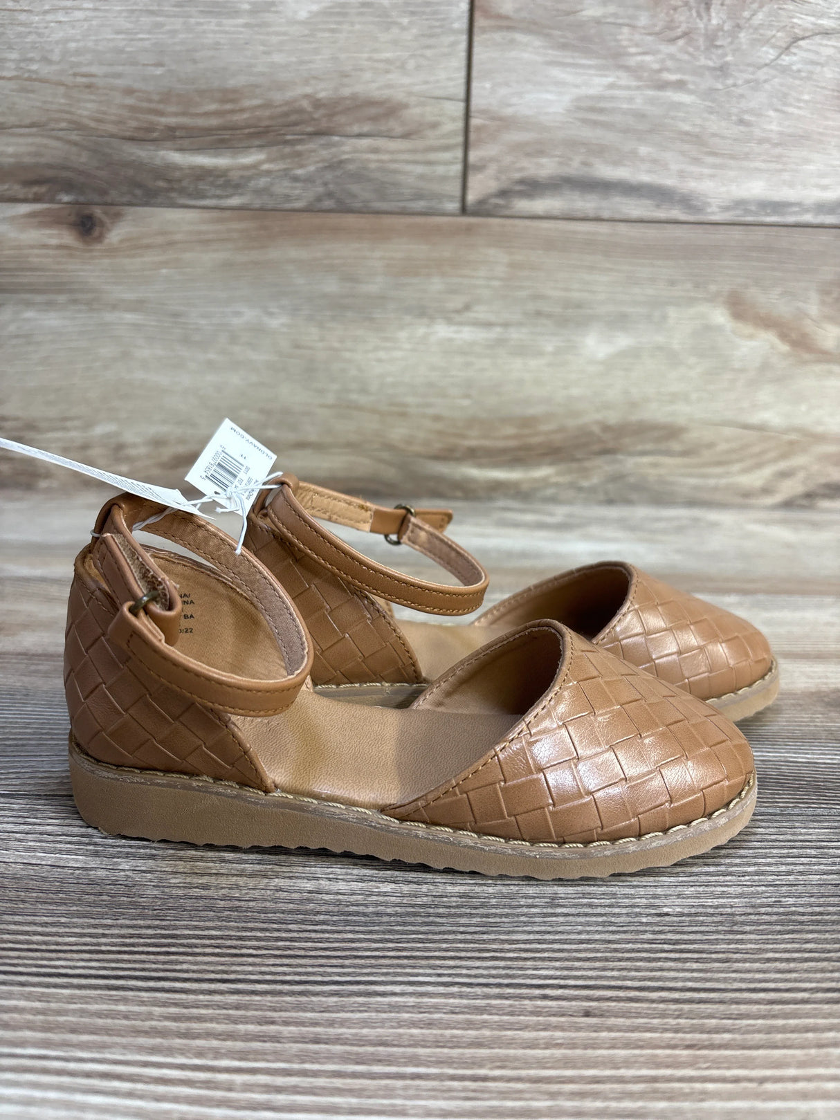 Tan woven toddler dress shoes with ankle straps on wooden background