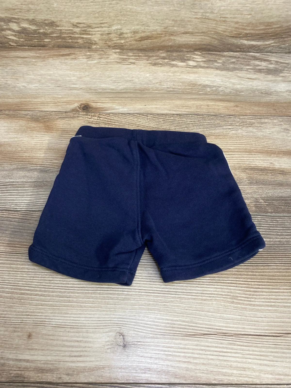 Flat lay of Boss Pull On Shorts sz 6m in navy French terry with elastic waistband and cuffed hems on wood plank floor