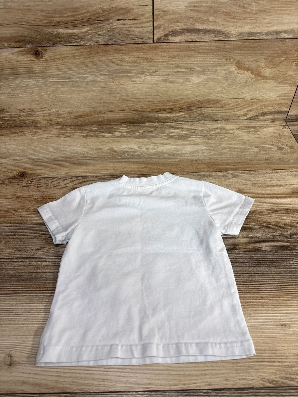 White short sleeve toddler t-shirt laid flat on wood background