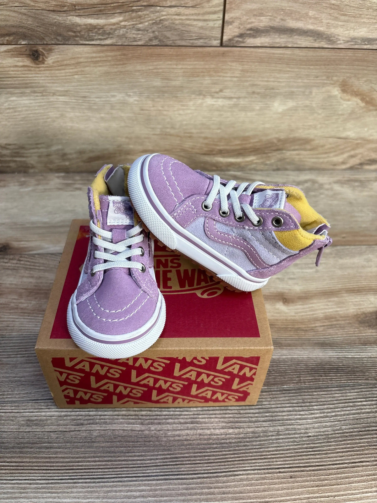 Front and side view of purple Vans MTE Sk8 Hi-Zip toddler sneakers showing white laces and back zippers on a wood background