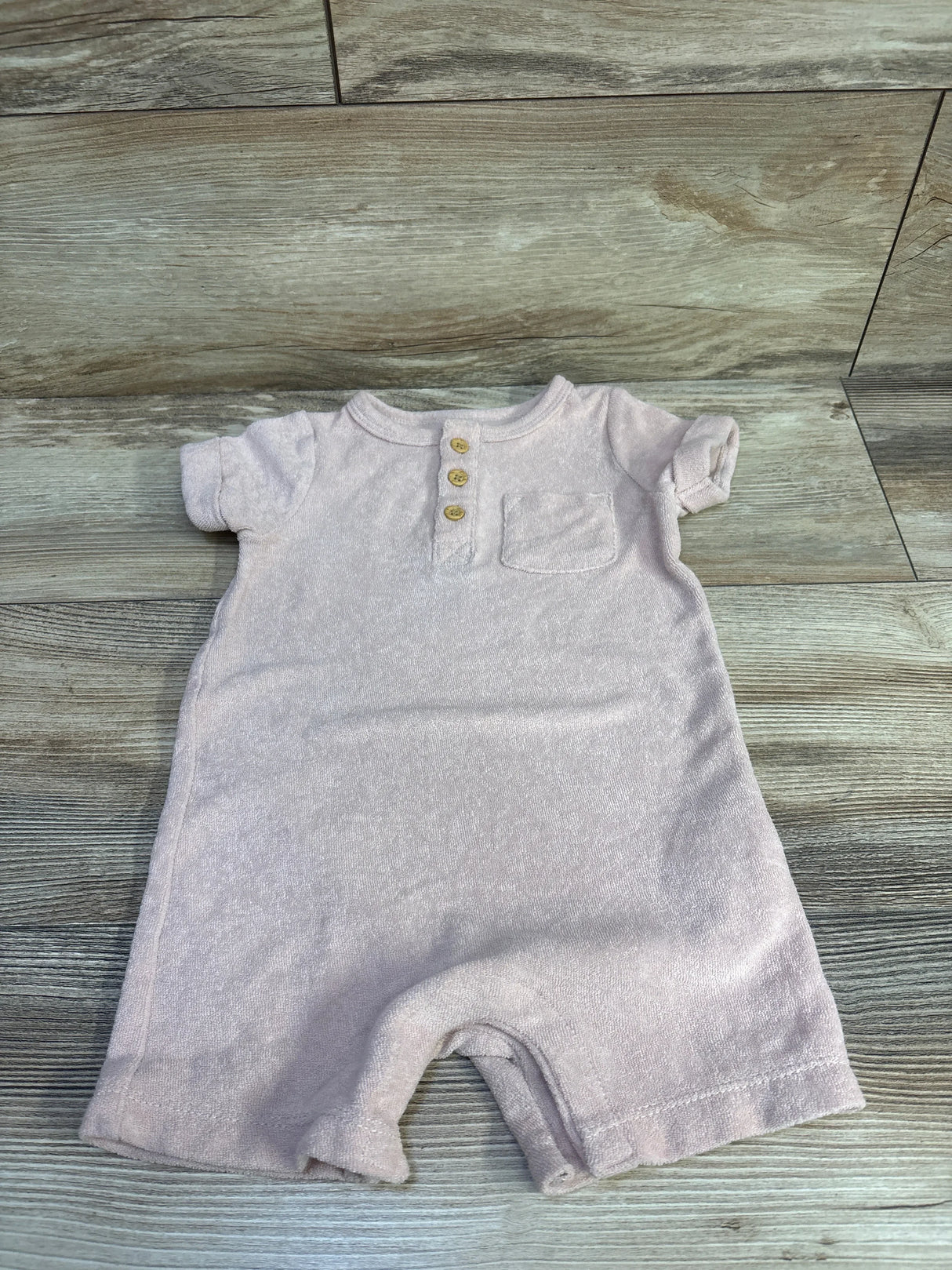 Top down view of Little Planet Organic henley terry romper (12m) showing three wooden buttons and chest pocket on wood floor