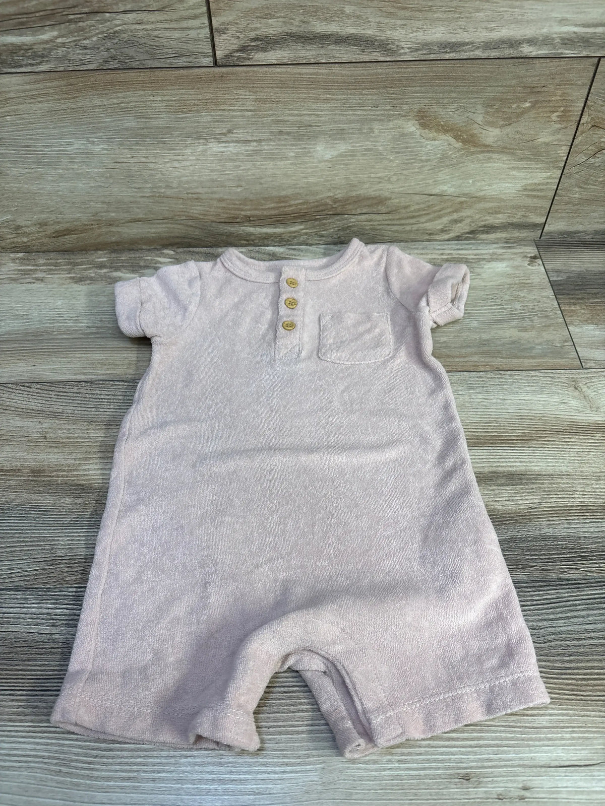 Top down view of Little Planet Organic henley terry romper (12m) showing three wooden buttons and chest pocket on wood floor