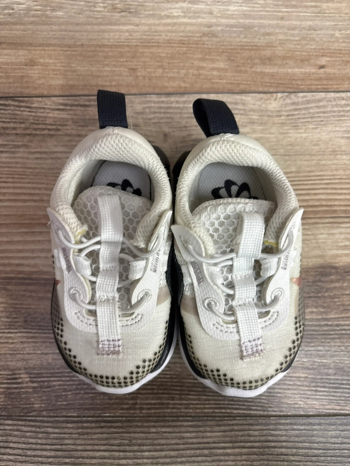 Top-down view of Nike Air Max 2021 TD in white with amethyst accents; mesh upper, elastic laces, navy heel pull tabs on wood