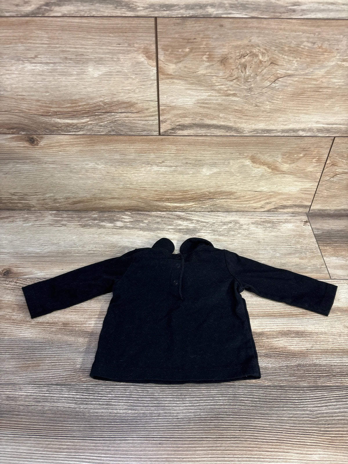 Front view of Cat & Jack black collared shirt, size 0 to 3 months, showcasing long sleeves on wood-look floor