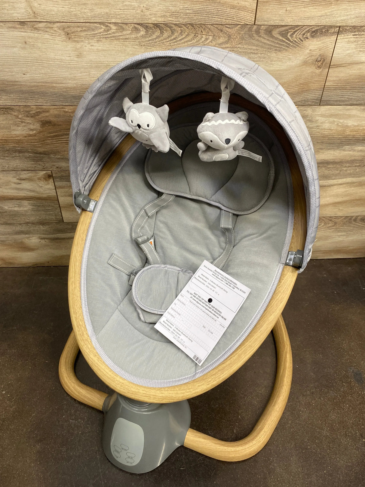 Modern baby bouncer seat with wooden frame, canopy, and plush animal toys, gently used.