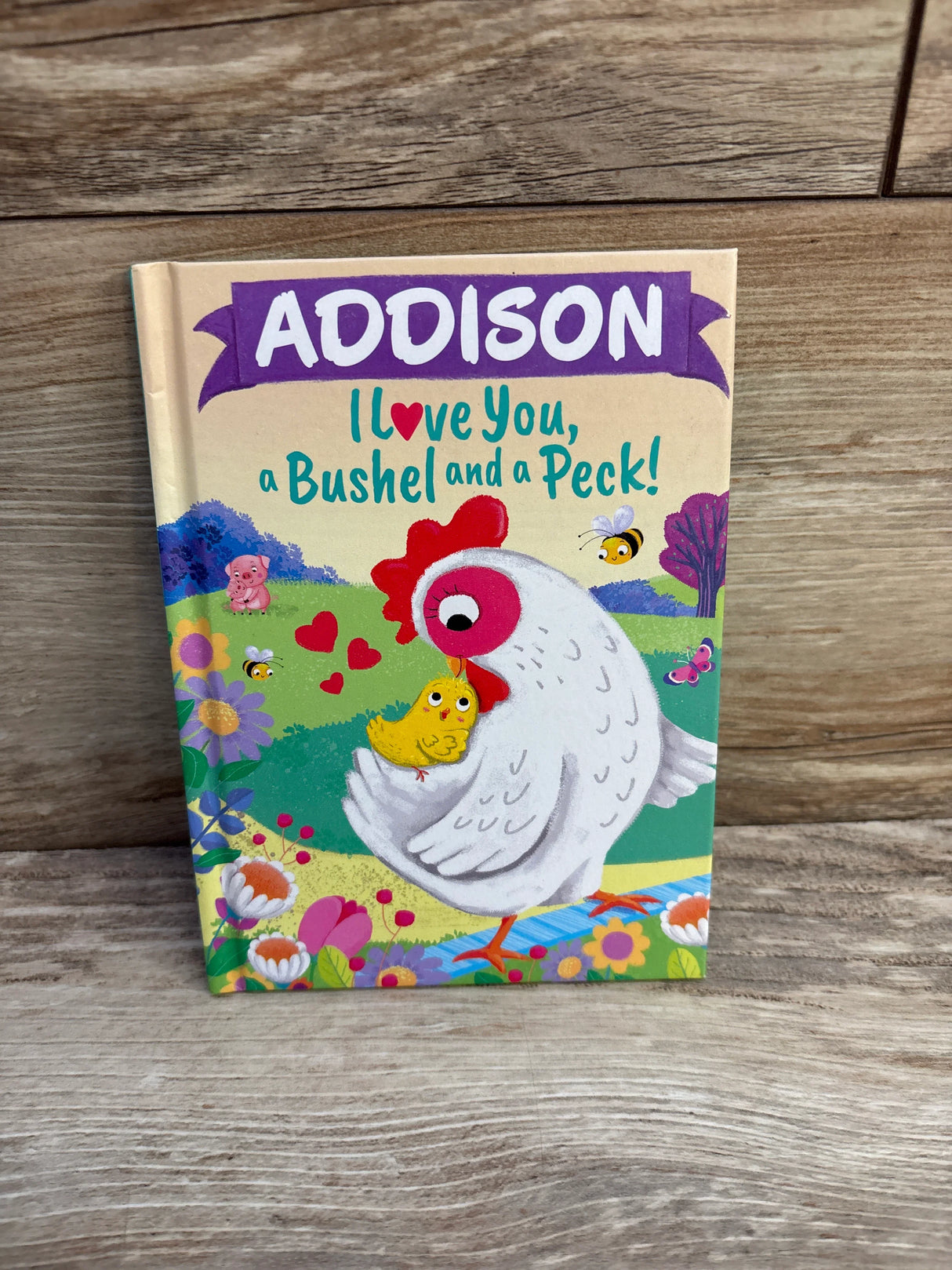 Children's book cover showing a hen hugging a chick with hearts and colorful garden background