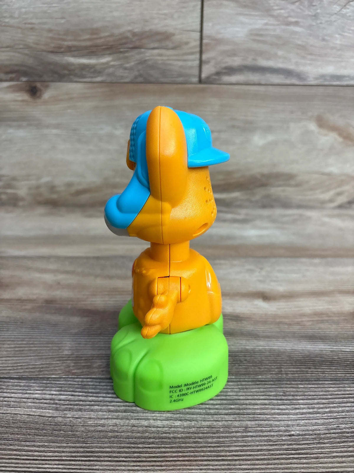 Side view of Fisher-Price Link Squad Opposites Fox Toy in orange with blue cap on green base on wood plank floor