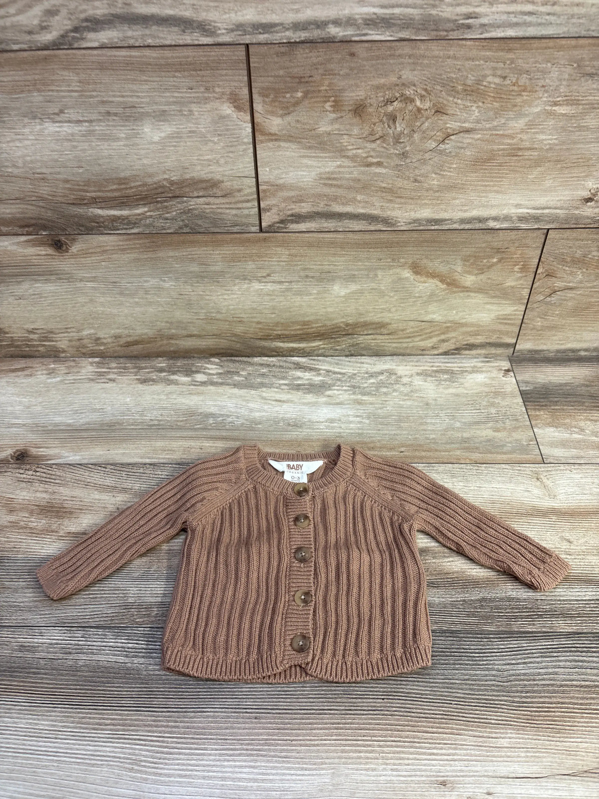 Brown organic knit baby cardigan with buttons by Me n Mommy To Be on a wood background