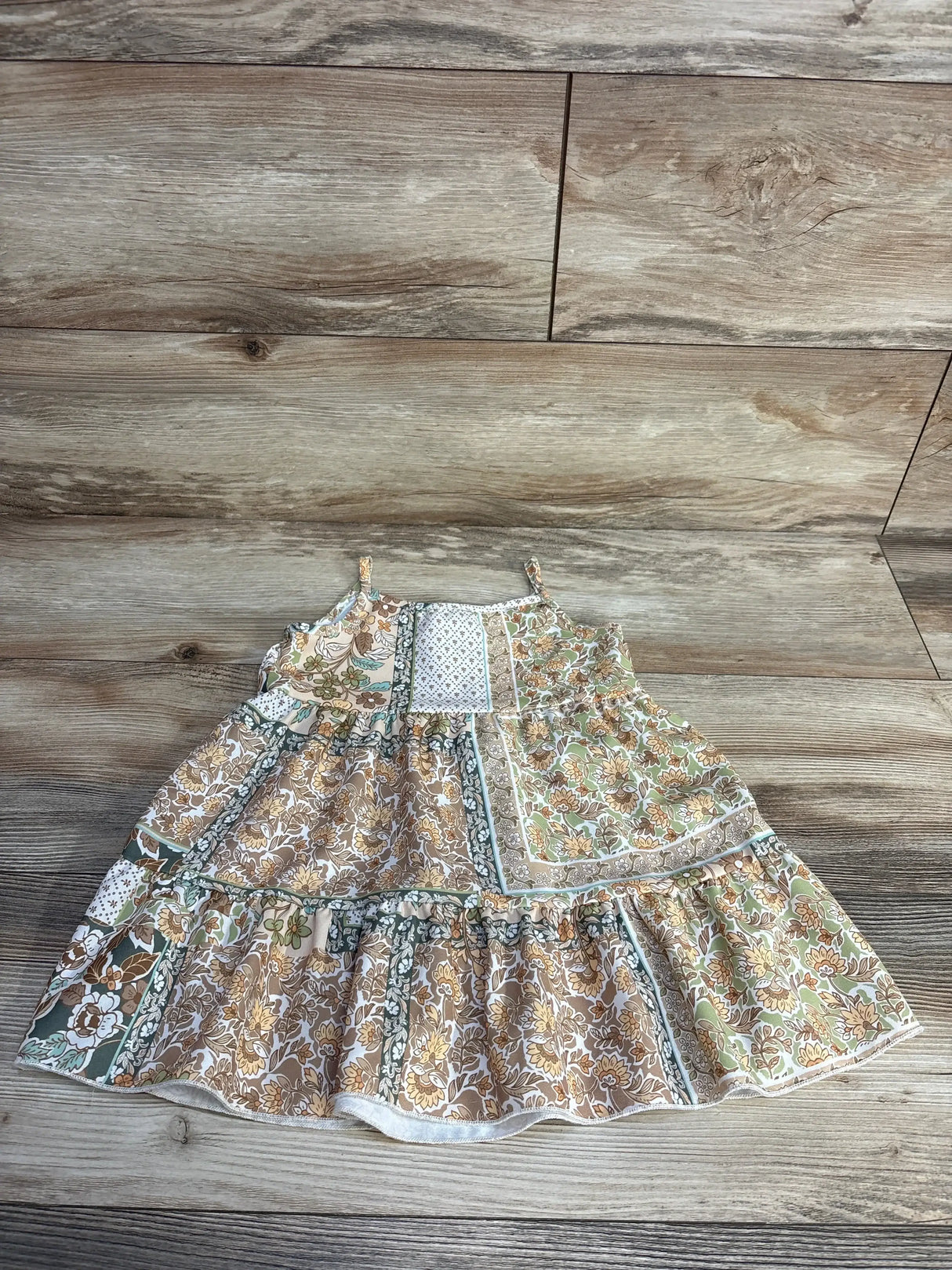 Flat lay of Tullabee floral tiered dress showcasing floral print, thin straps and ruffled tiers on wood background