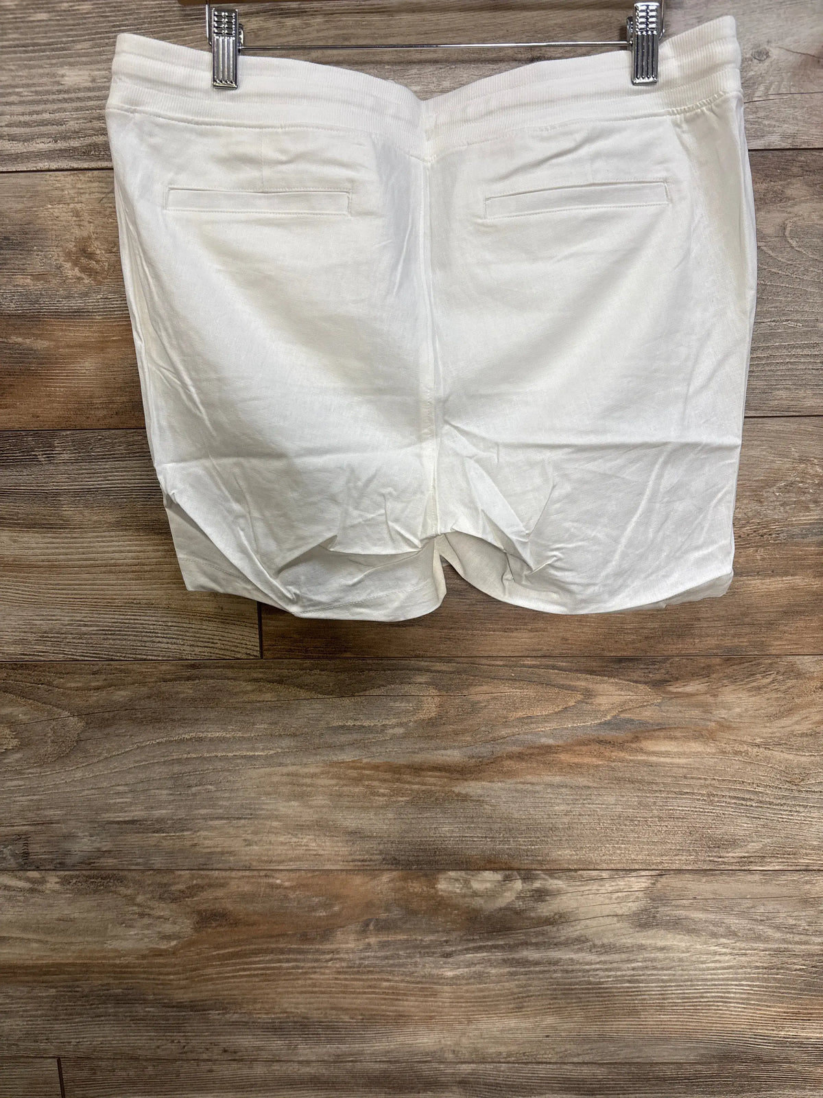 Back view of Gap maternity linen-blend shorts showcasing elasticized waist and back welt pockets on a wood floor