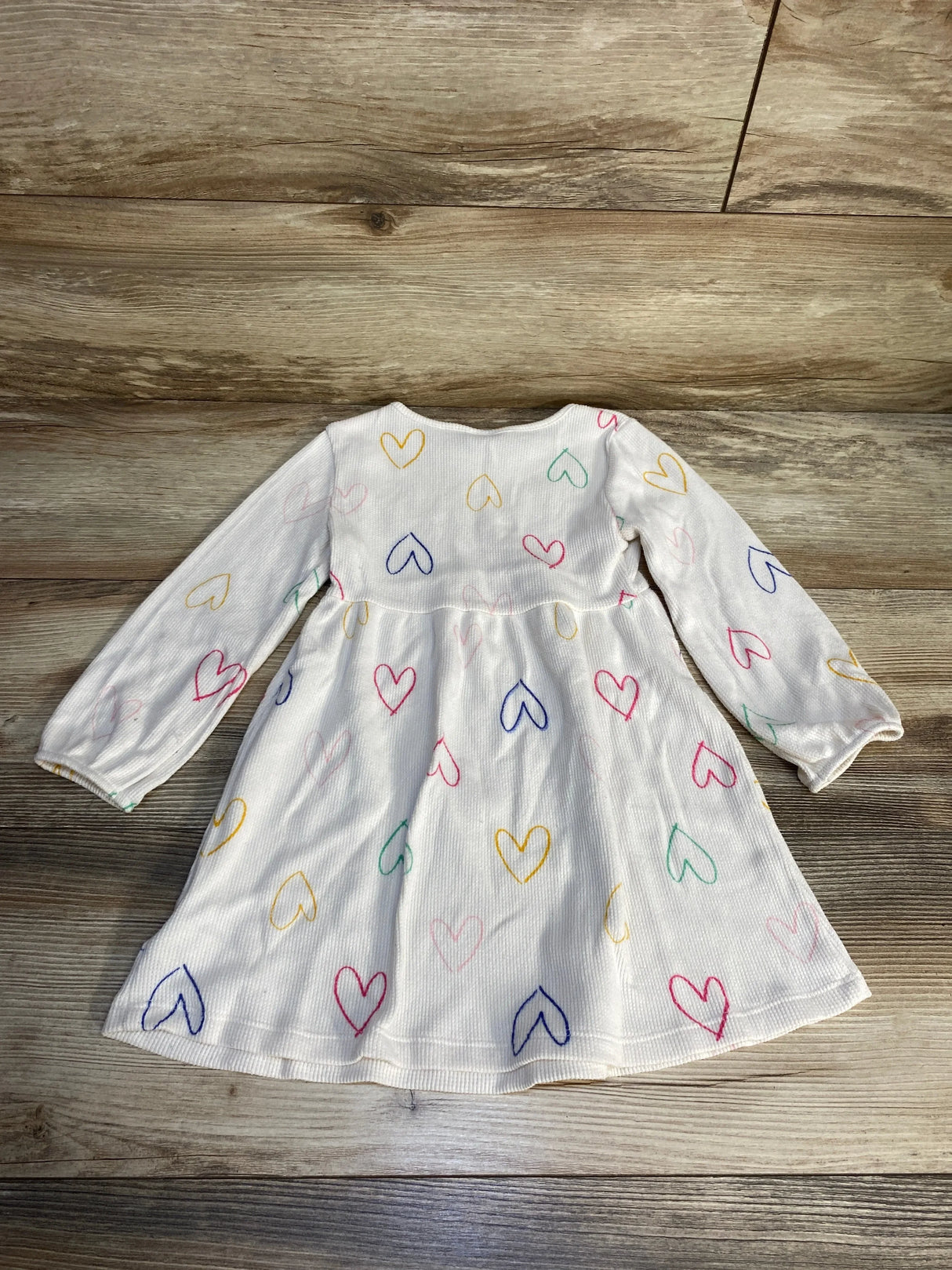 Flat lay of Old Navy white waffle-knit toddler dress 3T with multicolored heart print on wood background