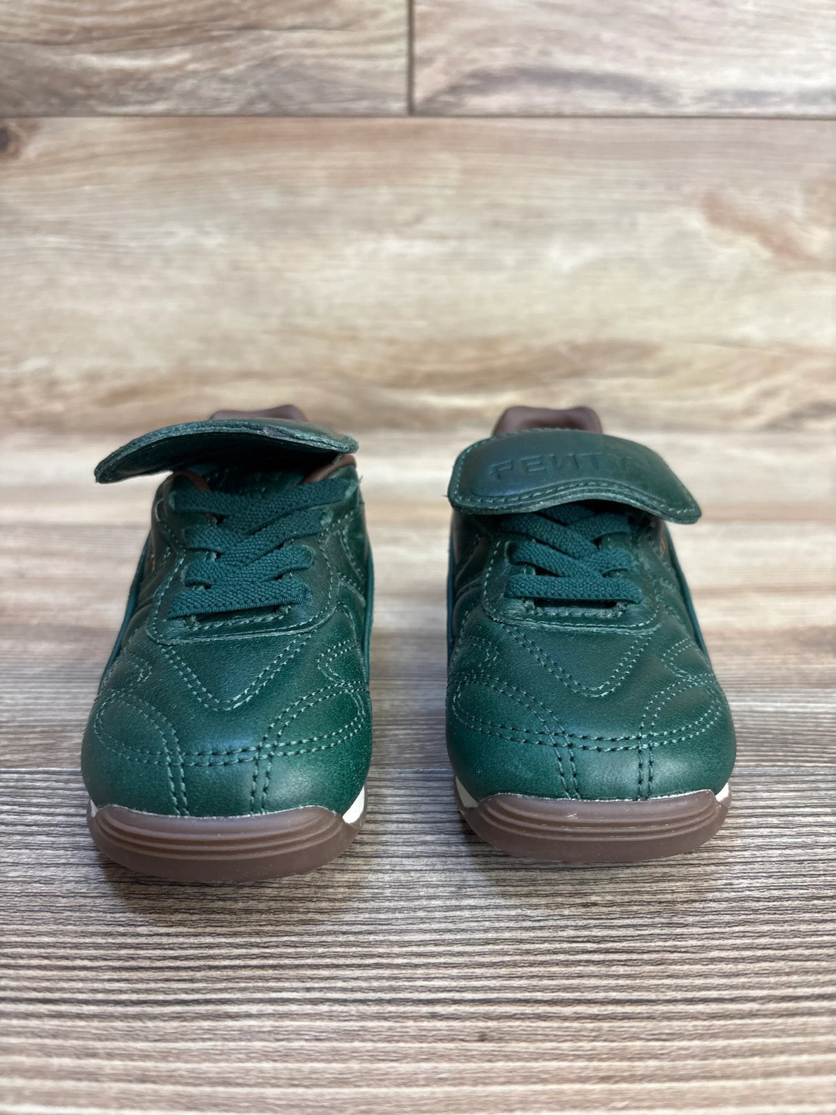 Front view of Puma x Fenty Avanti L sneakers showcasing leather uppers, foldable tongues, and gum outsoles on a wood floor