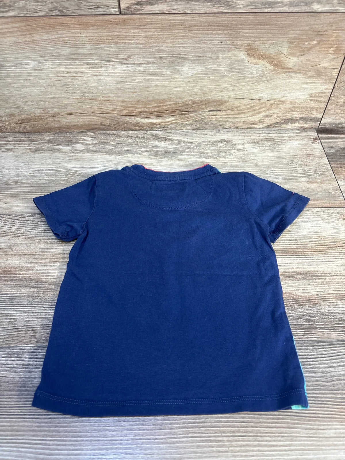 Navy blue short sleeve kids t-shirt laid flat on wood background