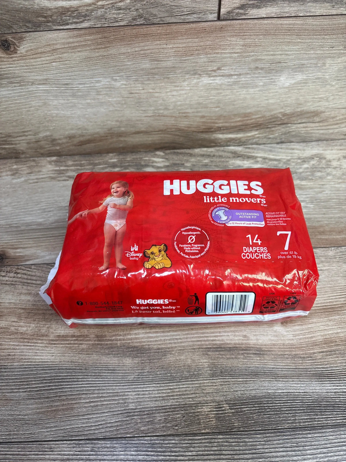 Front view of Huggies Little Movers size 7 diaper pack showcasing Disney Simba graphic and 14-count label on wood surface