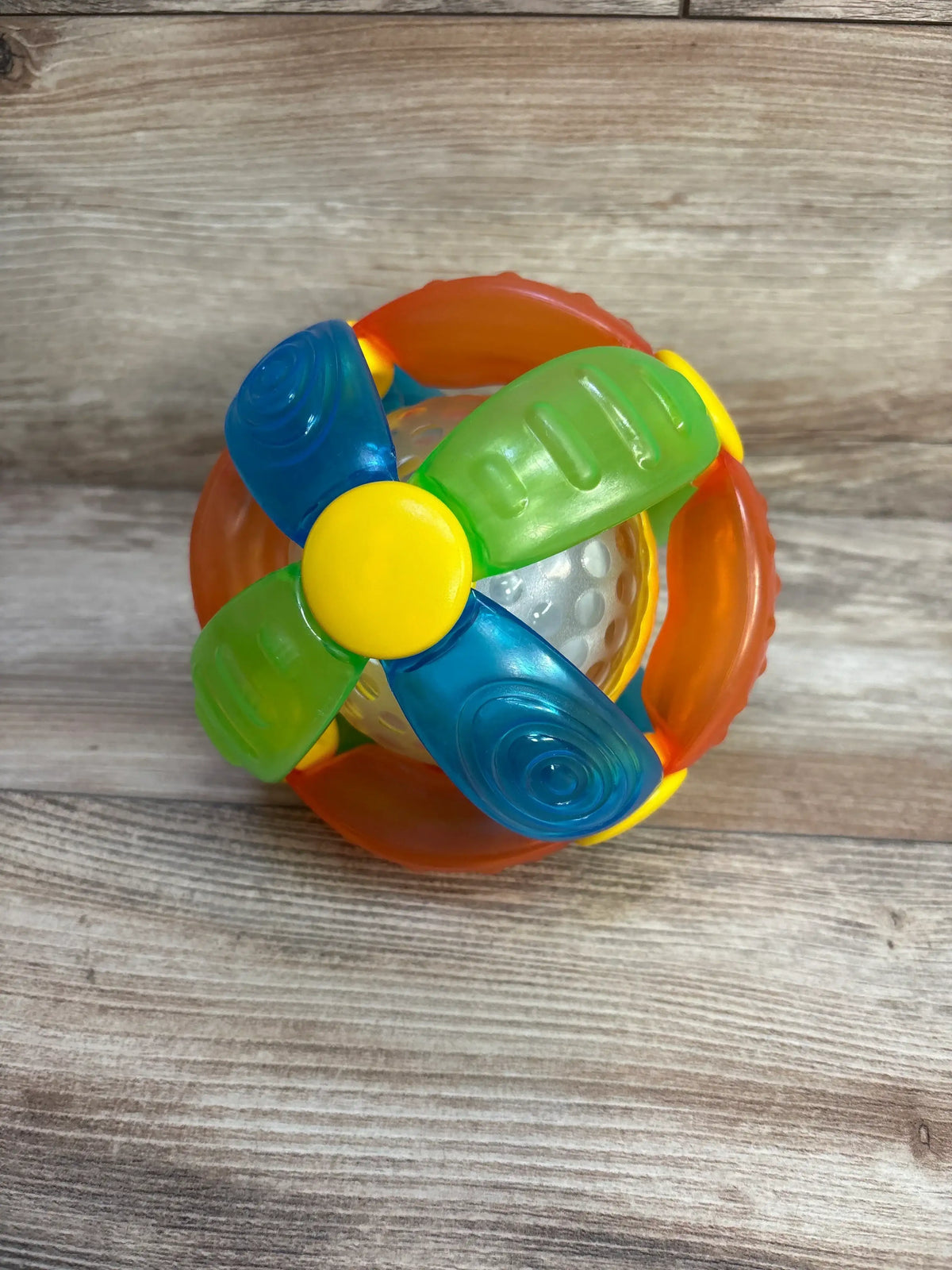 Top view of B Kids Blink’n Bling Ball showing translucent orange rings and textured light-up inner ball on wood background